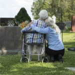 older woman in wheelchair & young woman facing a gravestone